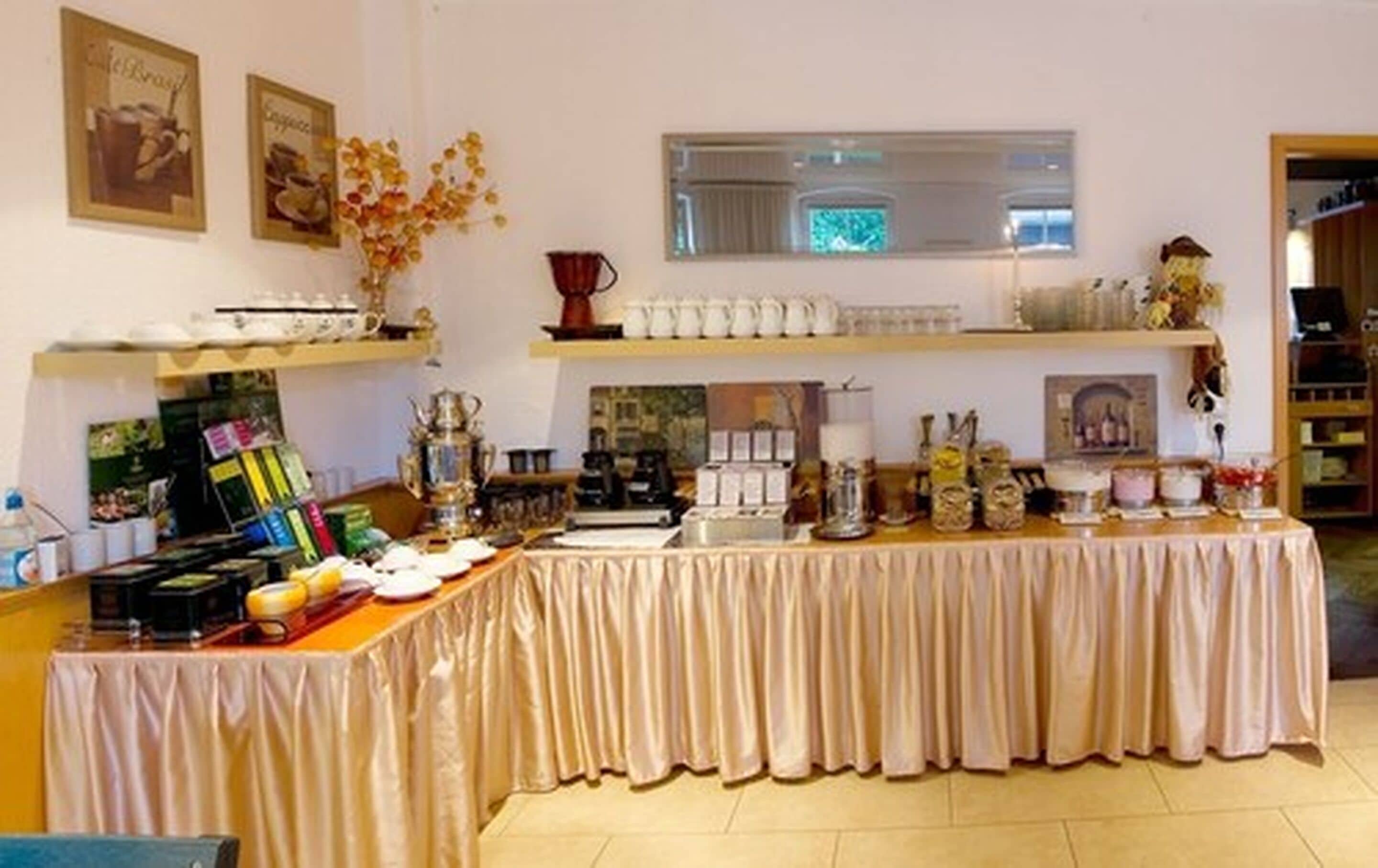 Un buffet proposant une variété de plats et de boissons, une machine à café et des éléments décoratifs tels que des photos encadrées et un vase rempli de fleurs.