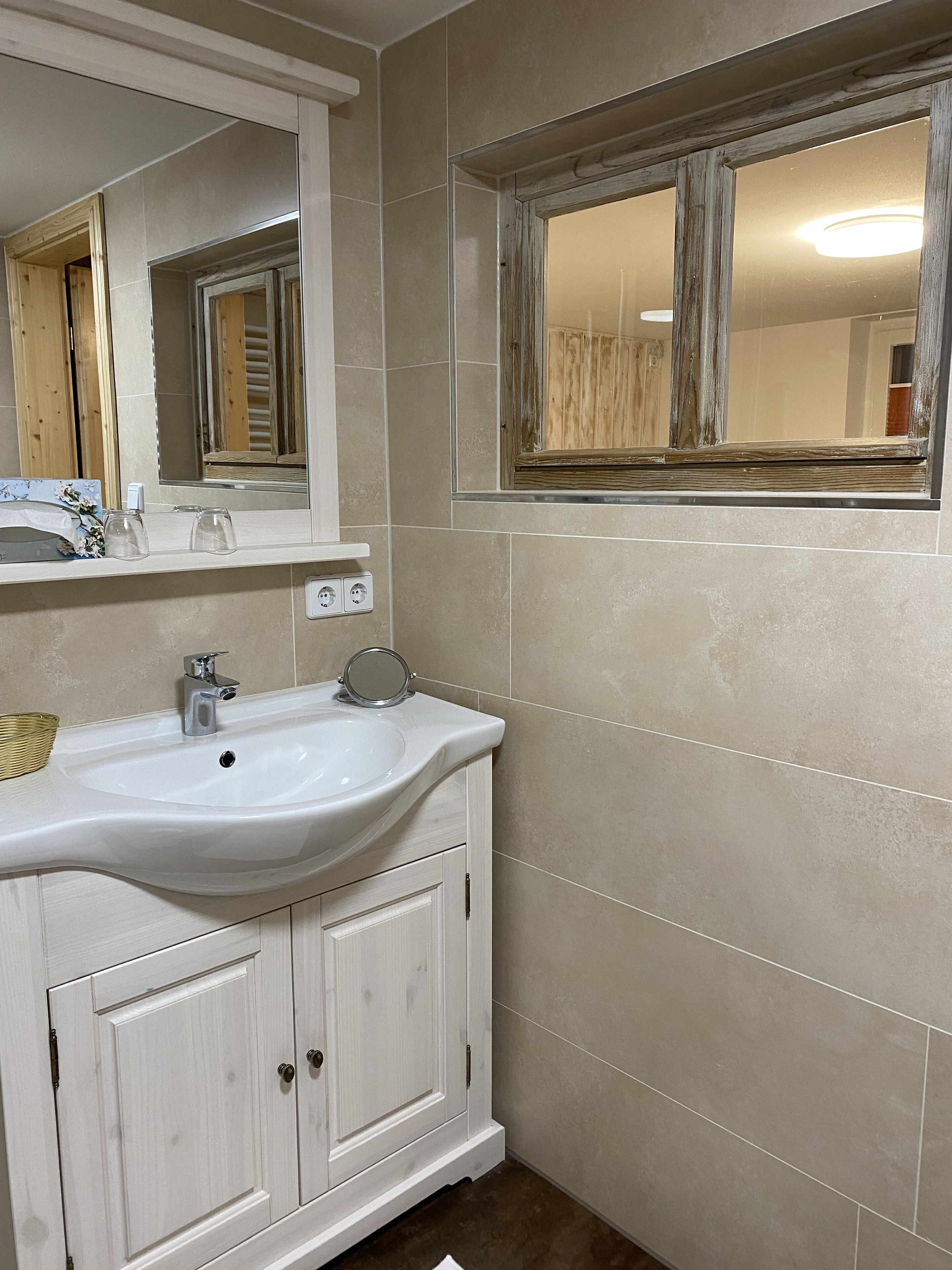 A bathroom with a white sink, mirror, and wooden cabinets.