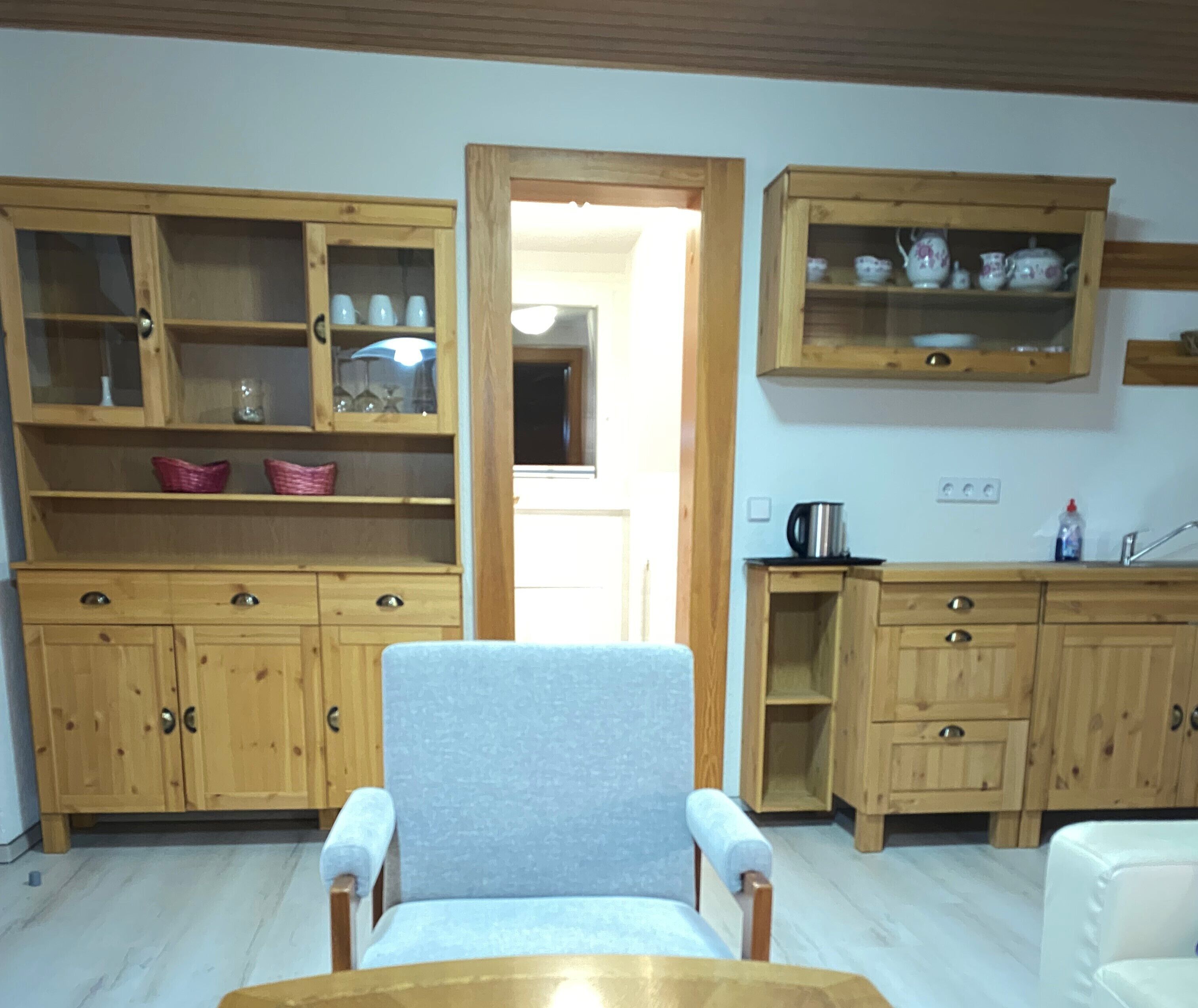 A compact kitchen with wooden cabinets, a dining chair, and a small table.
