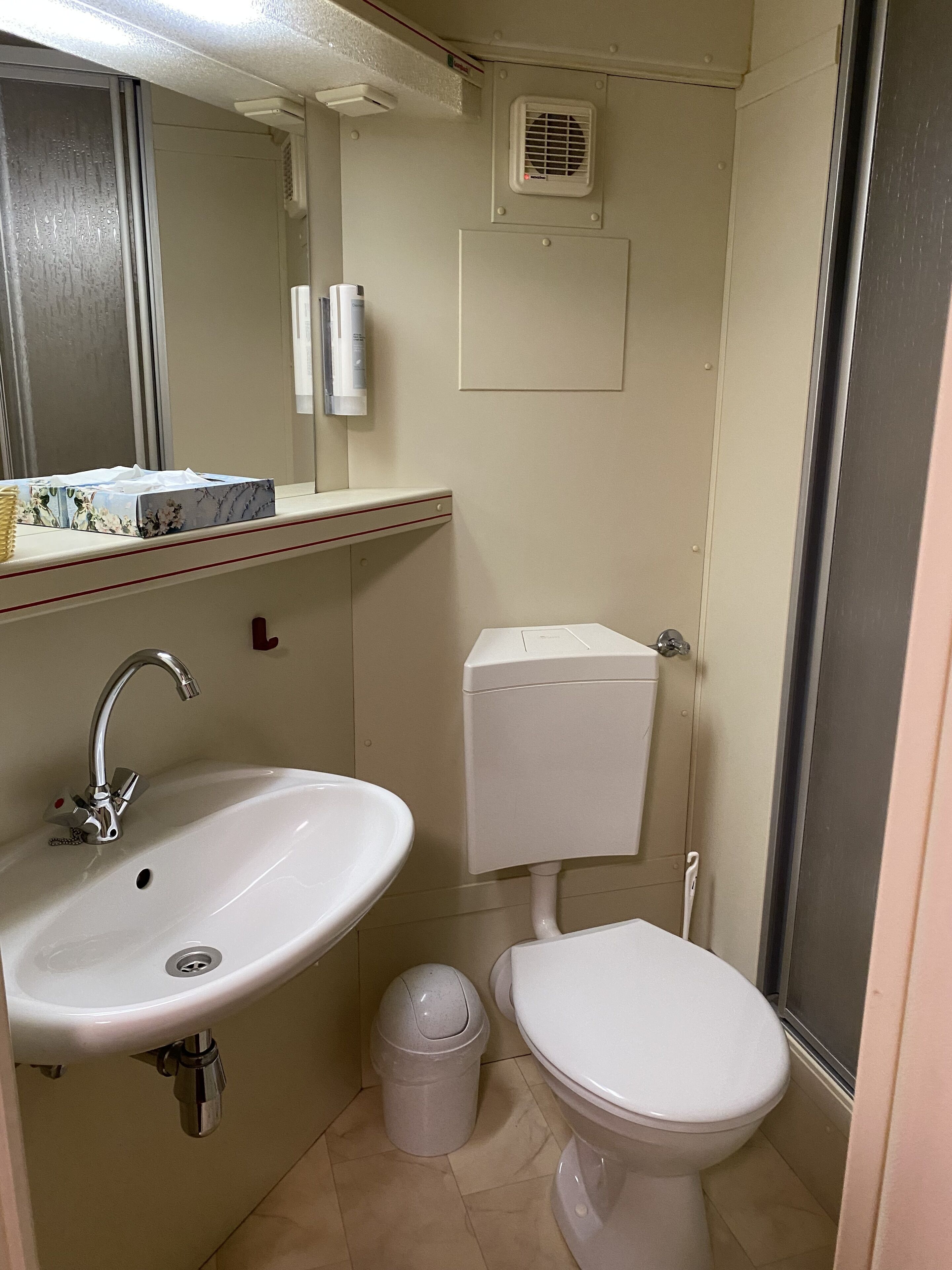 Een kleine badkamer met een wastafel, toilet en spiegel.
