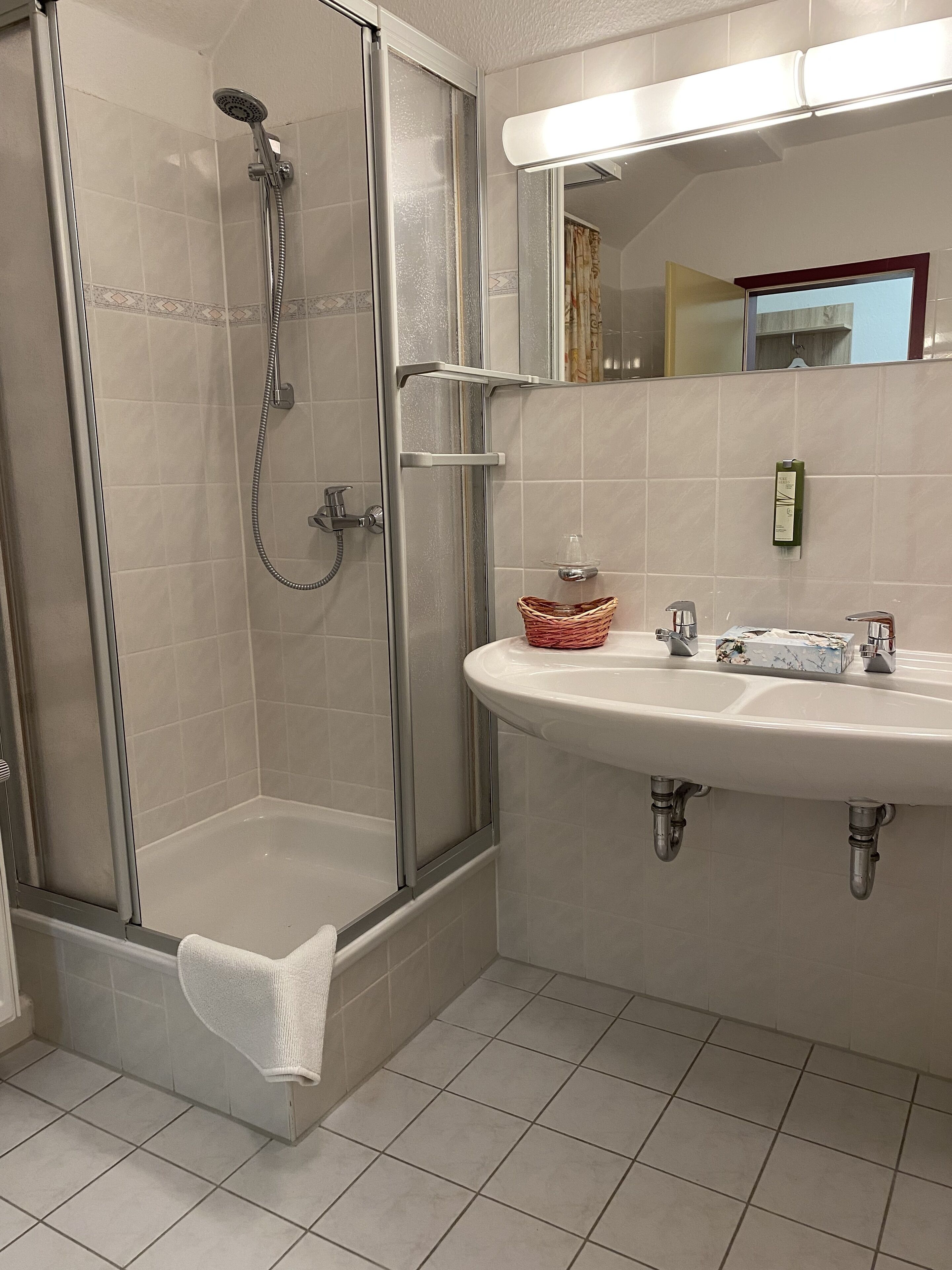 A bathroom with a glass-enclosed shower, a sink with a marble countertop, and a mirror above the sink.