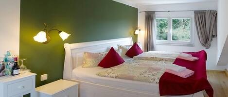 A bedroom with a bed, nightstands, a lamp, and a window with curtains.