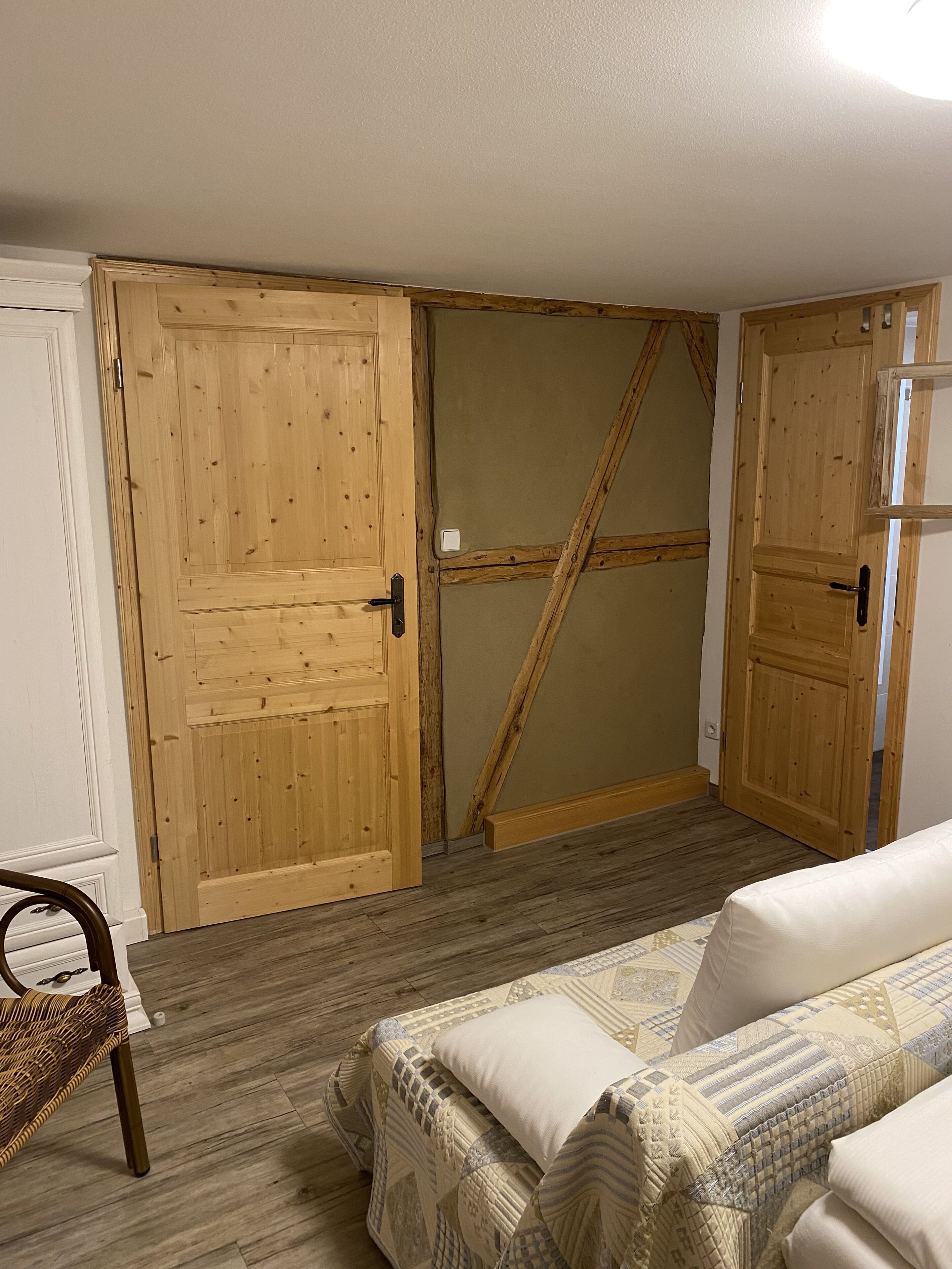 Une pièce avec une armoire en bois, un lit avec une literie à motifs et une chaise en osier.