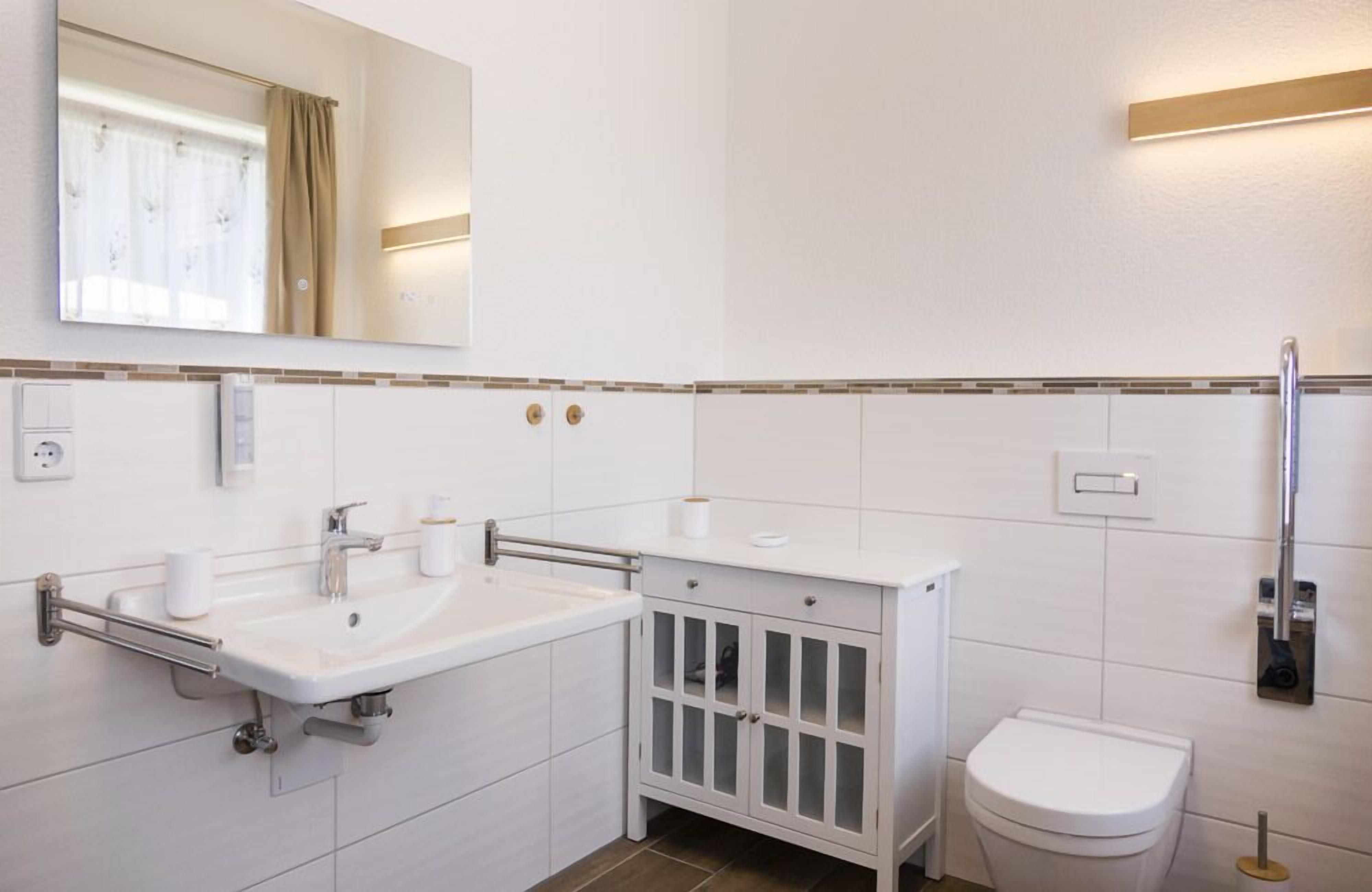 A modern bathroom with a white sink, mirror, and toilet.