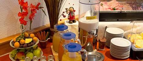 A buffet setup with various food items, including fruits, vegetables, and beverages.