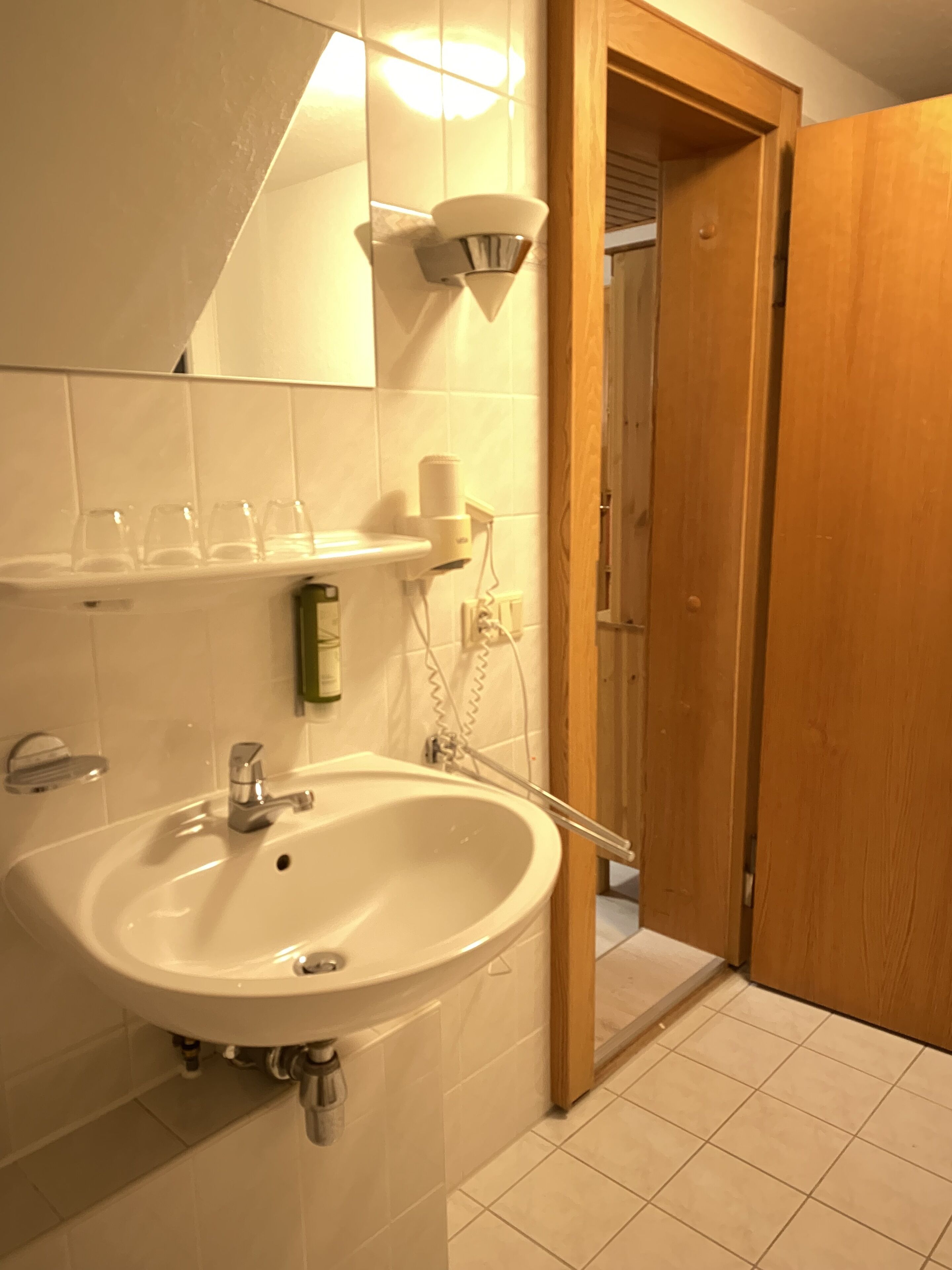 A bathroom with a white sink, a mirror, and a wooden door.