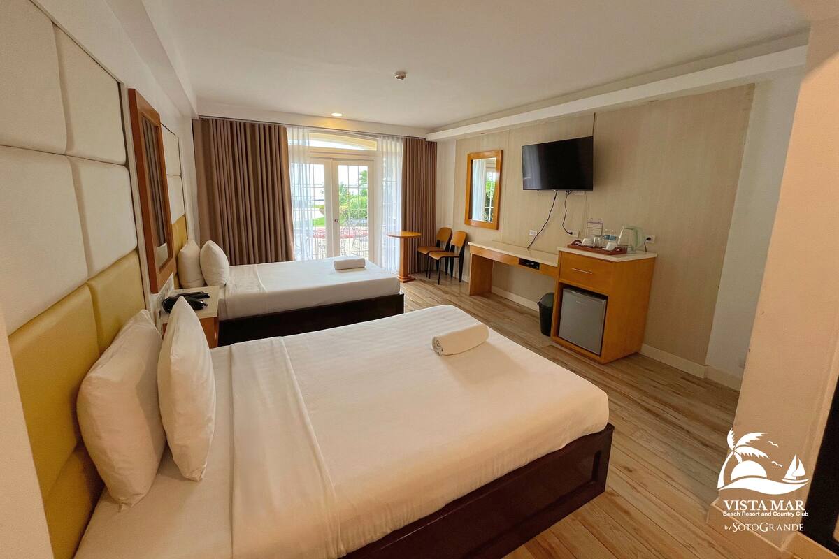 Une chambre d’hôtel avec deux lits, un bureau, une télévision et un minibar.
