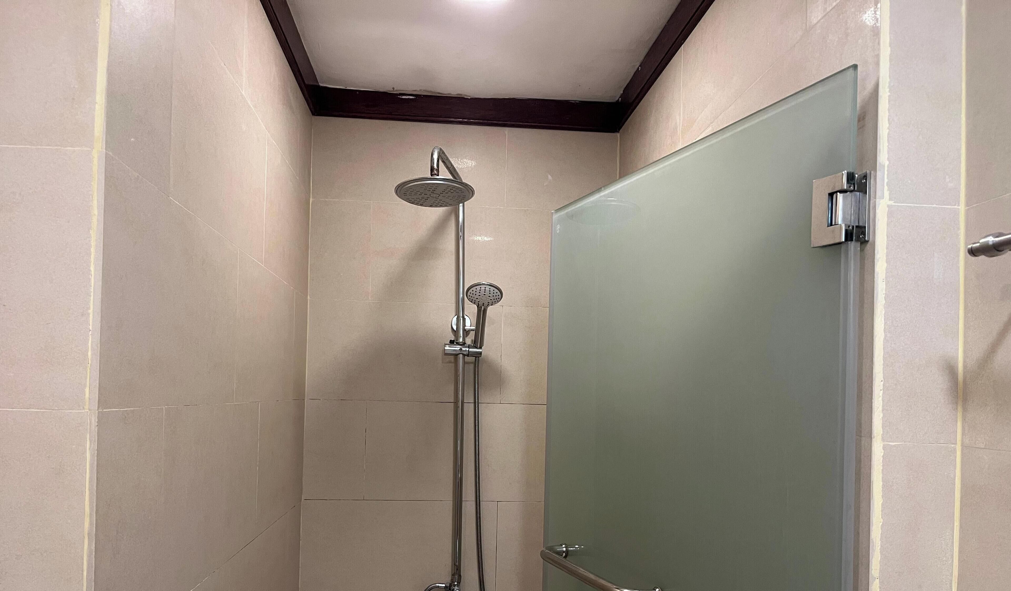 A small, tiled shower area with a glass door and a showerhead.