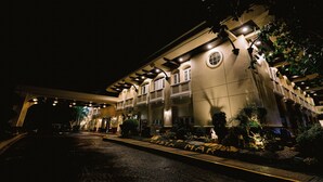 Un hotel de varios pisos con un patio central, iluminación exterior y un jardín bien cuidado.