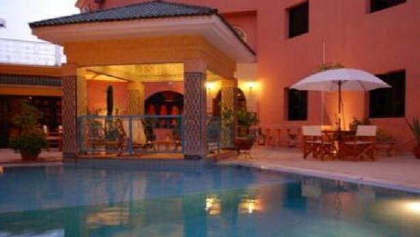 A swimming pool with a covered seating area and a patio with outdoor furniture. - Dar Naciria Marrakech (Marrakech)