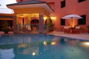 A swimming pool with a covered seating area and a patio with outdoor furniture. - Dar Naciria Marrakech (Marrakech)
