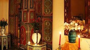 A room with ornate wooden paneling, a mirror, and a table with a vase and candles. - Dar Naciria Marrakech (Marrakech)