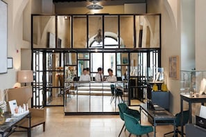 A reception area with a glass partition, a chandelier, and a desk with a laptop. - Castel Monastero - The Leading Hotels of the World (Castelnuovo Berardenga)