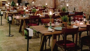 A restaurant with brick walls, wooden tables, and hanging lanterns. - Castel Monastero - The Leading Hotels of the World (Castelnuovo Berardenga)