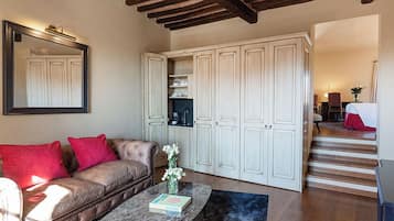 A living room with a leather sofa, a coffee table, and a mirror. There are white cabinets and a staircase leading to another room.