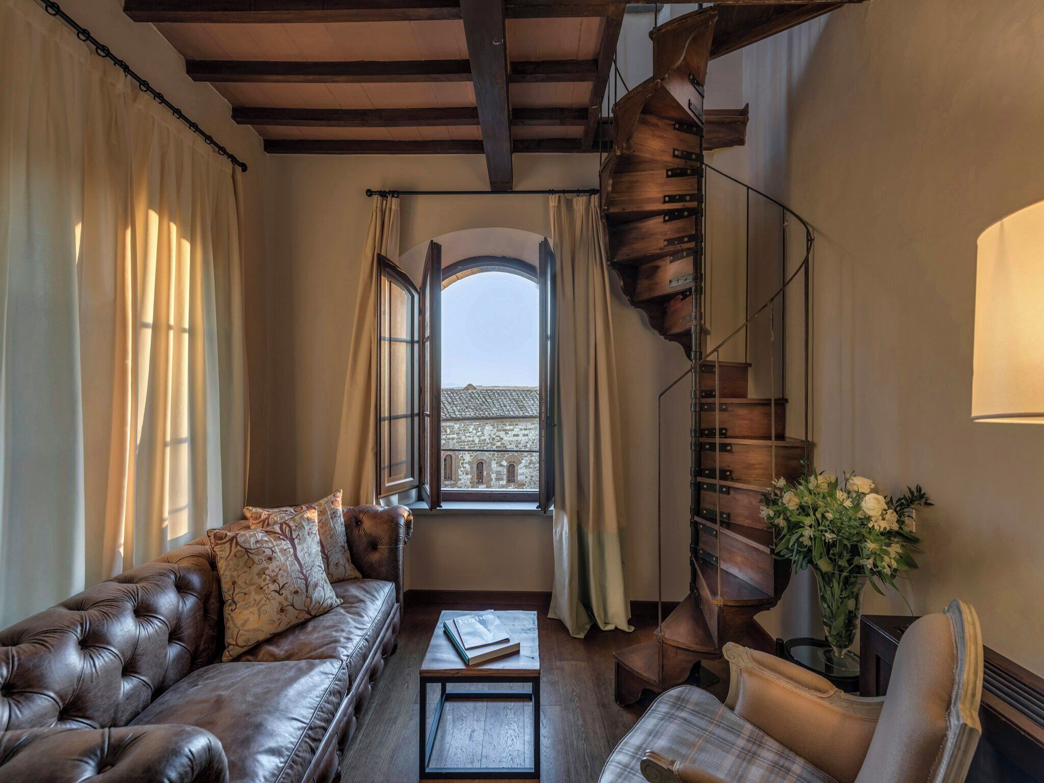 Una sala de estar acogedora con un sofá de cuero, una mesa de centro y una escalera en espiral.