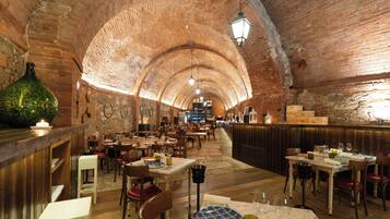 A restaurant with brick arches, wooden tables, and a bar area.