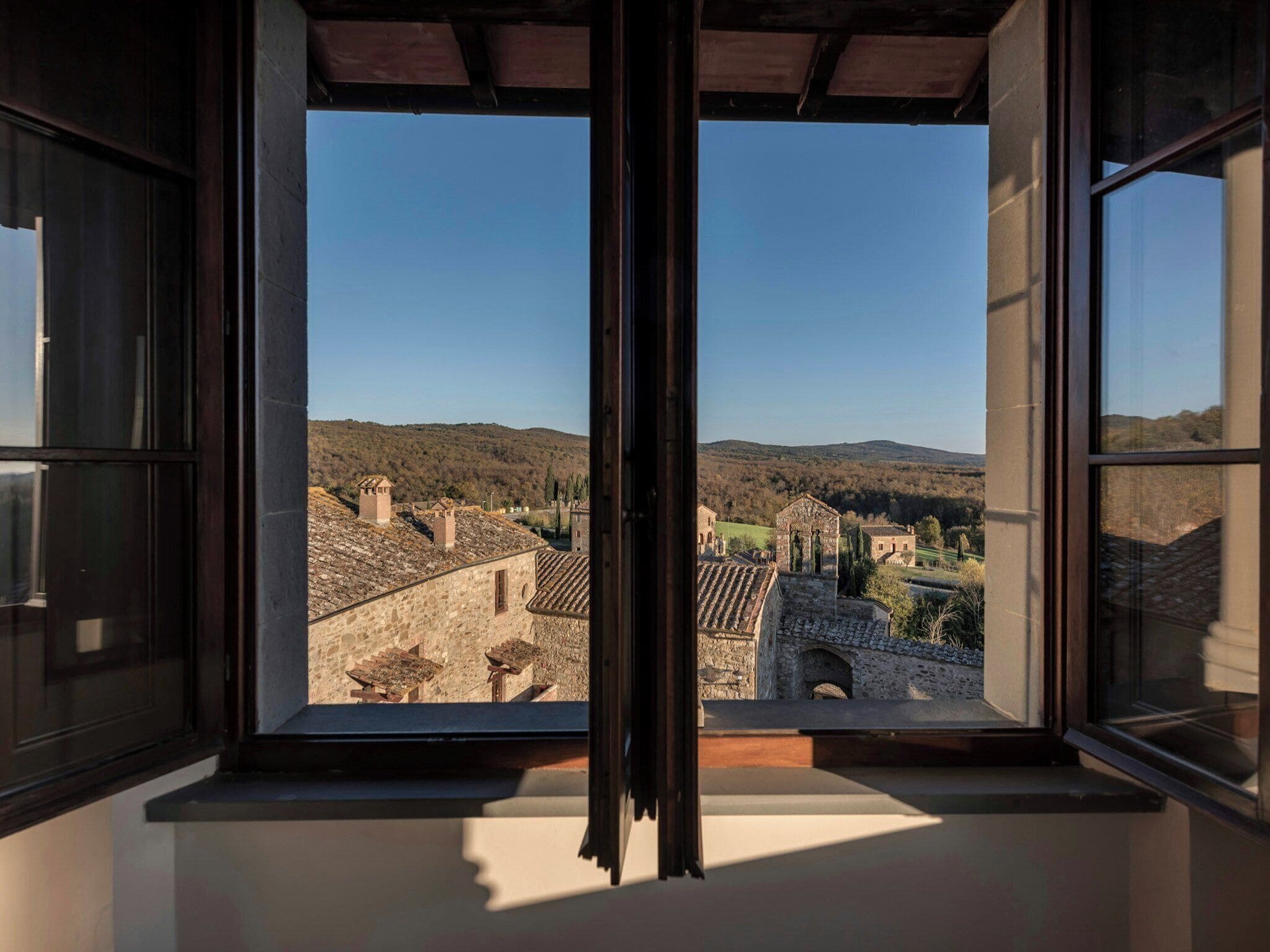 Una finestra con vista su una città storica, edifici in pietra e cielo sereno.