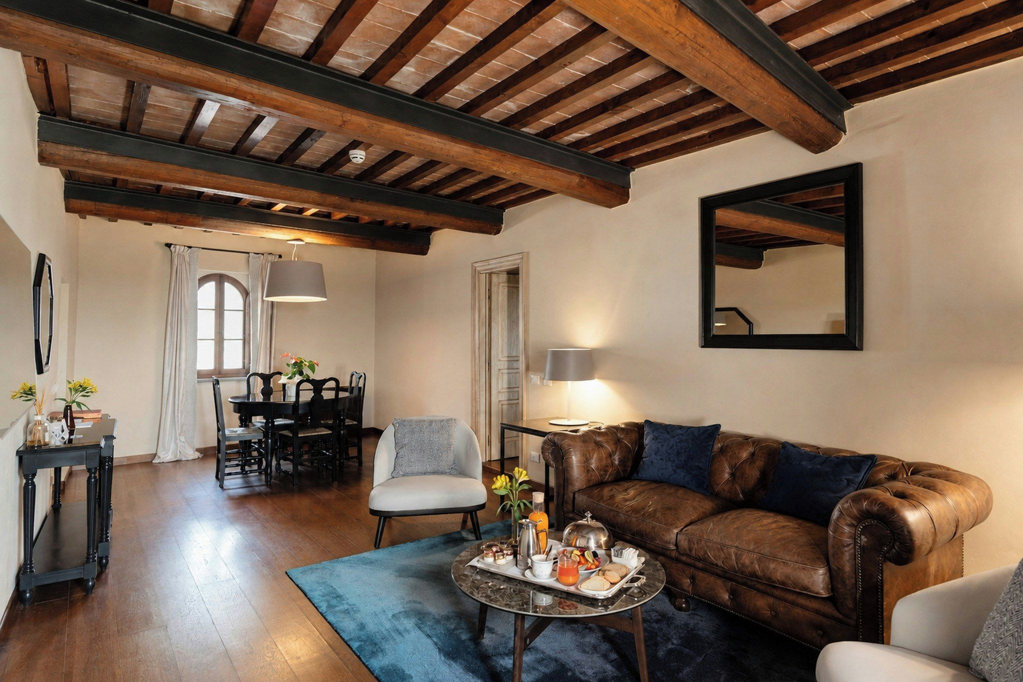 Ein gemütliches Wohnzimmer mit einem Ledersofa, einem Esstisch mit Stühlen und einem Couchtisch mit einer Platte Essen.