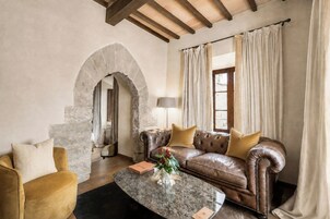 Una sala de estar con un sofá de cuero, una mesita de centro y un arco de piedra.