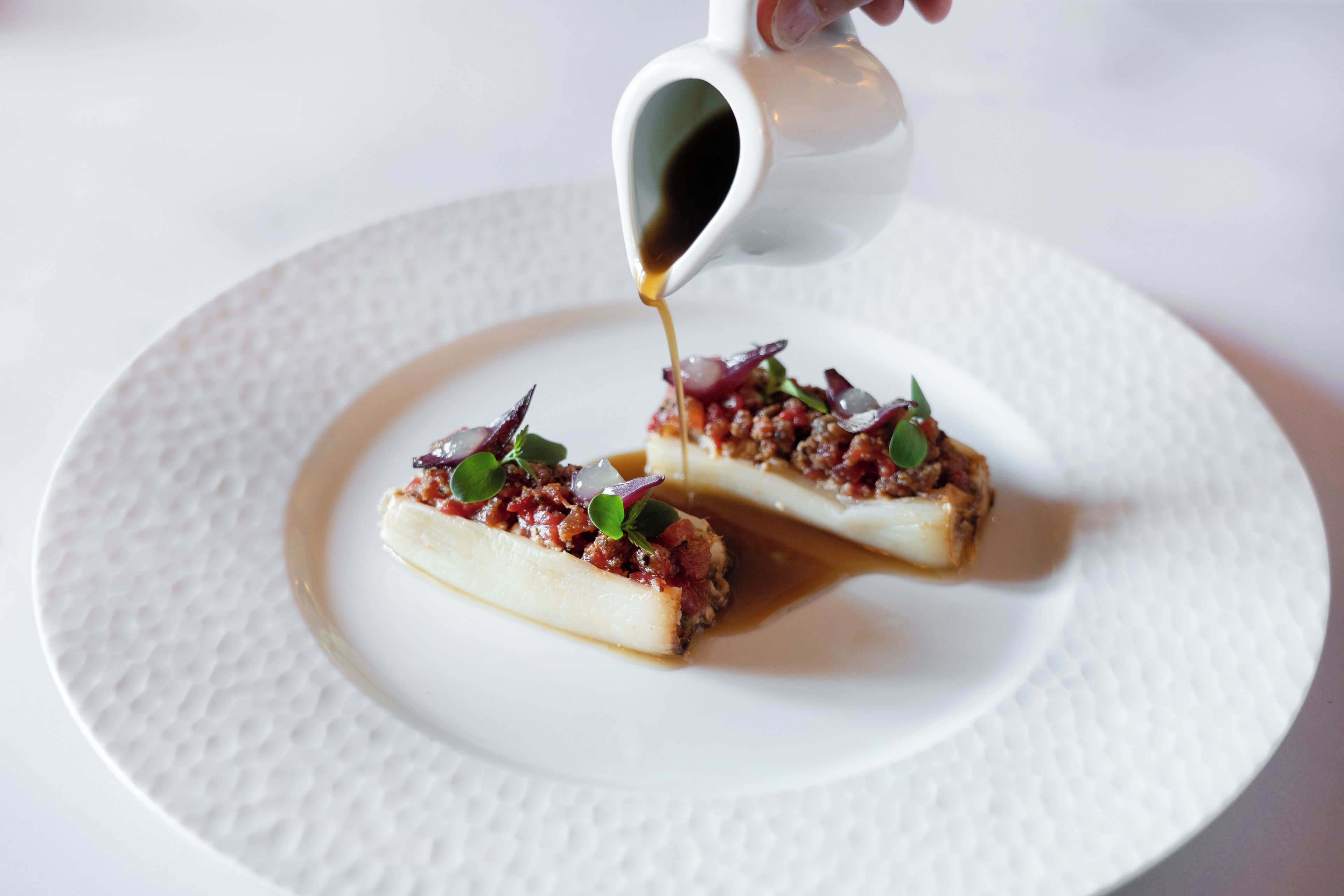 Un plato blanco con un alimento cubierto de salsa y adornos.
