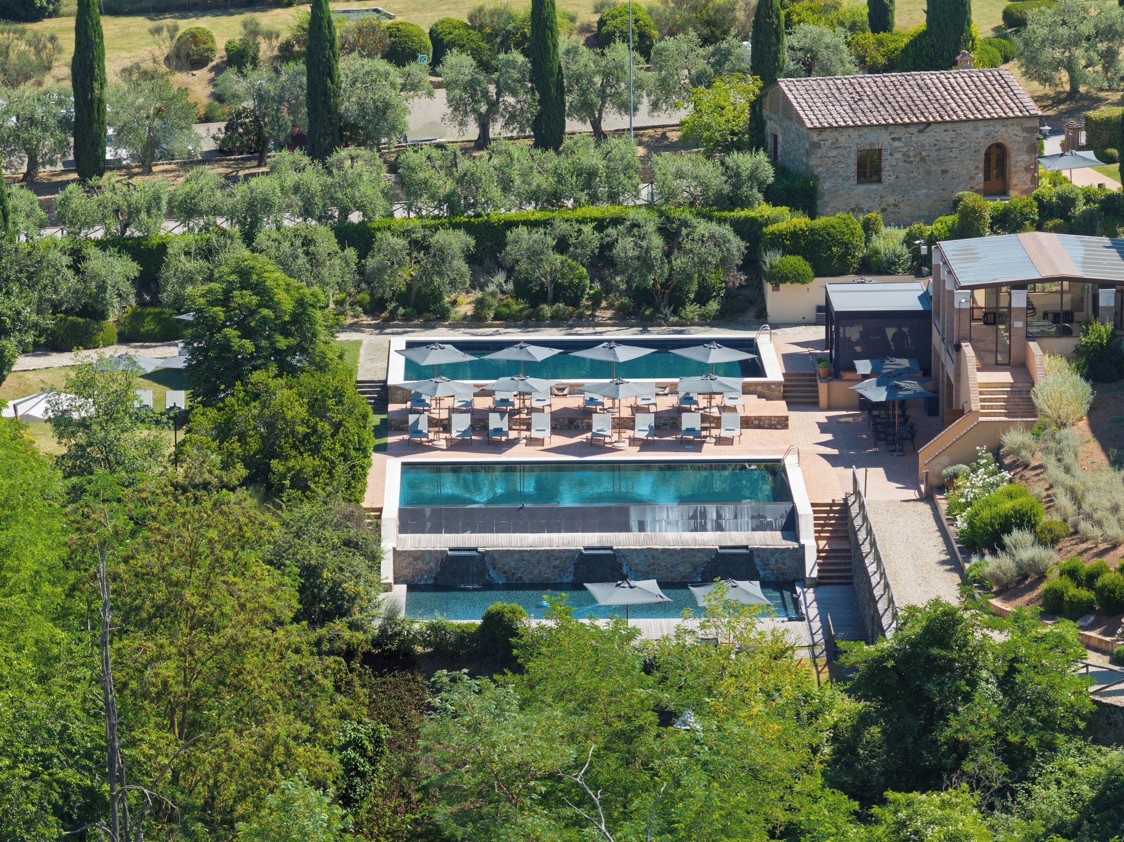 Ein Resort mit mehreren Schwimmbecken, Außenbereichen zum Sitzen und einem Gebäude aus Stein.