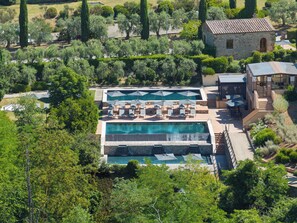 A resort with multiple swimming pools, outdoor seating areas, and a stone building. - Castel Monastero - The Leading Hotels of the World (Castelnuovo Berardenga)