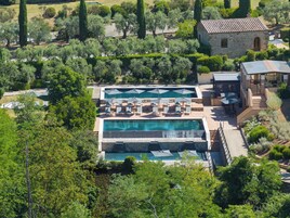 Un complejo turístico con varias piscinas, zonas de estar al aire libre y un edificio de piedra.