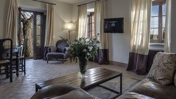 A living room with a wooden coffee table, a sofa, a chair, and a TV mounted on the wall.