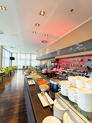 A buffet with various food stations, a coffee bar, and seating areas with tables and chairs.