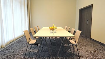 Un salón de conferencias con una mesa rectangular, ocho sillas, un frutero y una puerta.