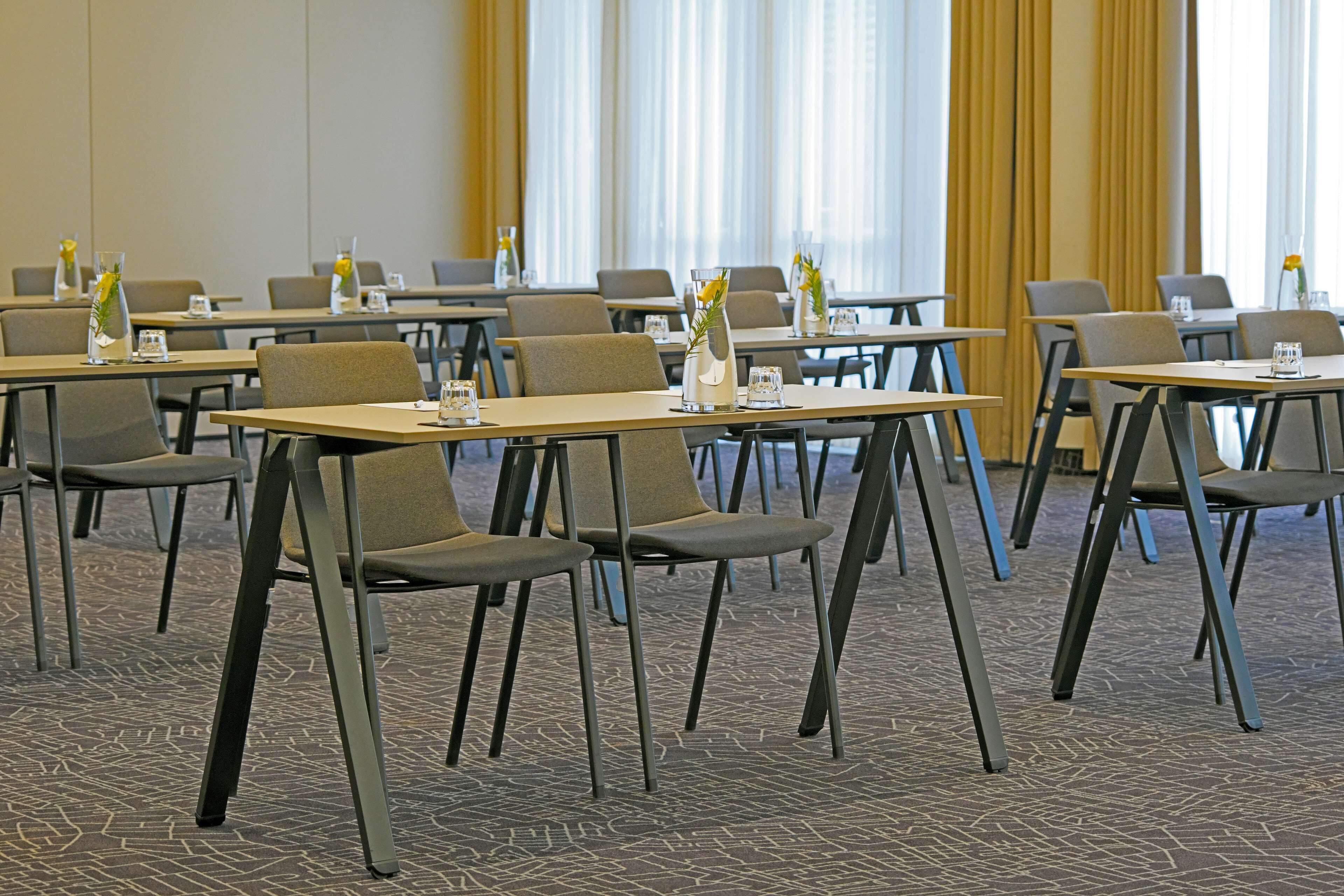 Un salón de conferencias con mesas y sillas, dispuesto para una reunión.