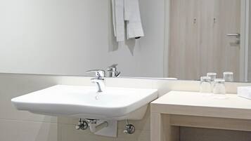 A modern bathroom with a white sink, a mirror, and a towel rack.