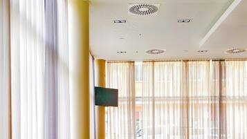 Un restaurante con sillas y mesas amarillas, y un televisor montado en la pared.