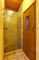 Un pasillo estrecho con una puerta de madera y un cerramiento de ducha de vidrio.
