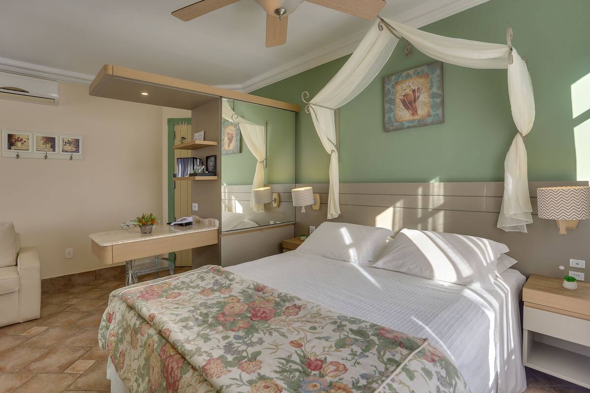 Un dormitorio con cama, escritorio, silla, mesita de noche y ventilador de techo.