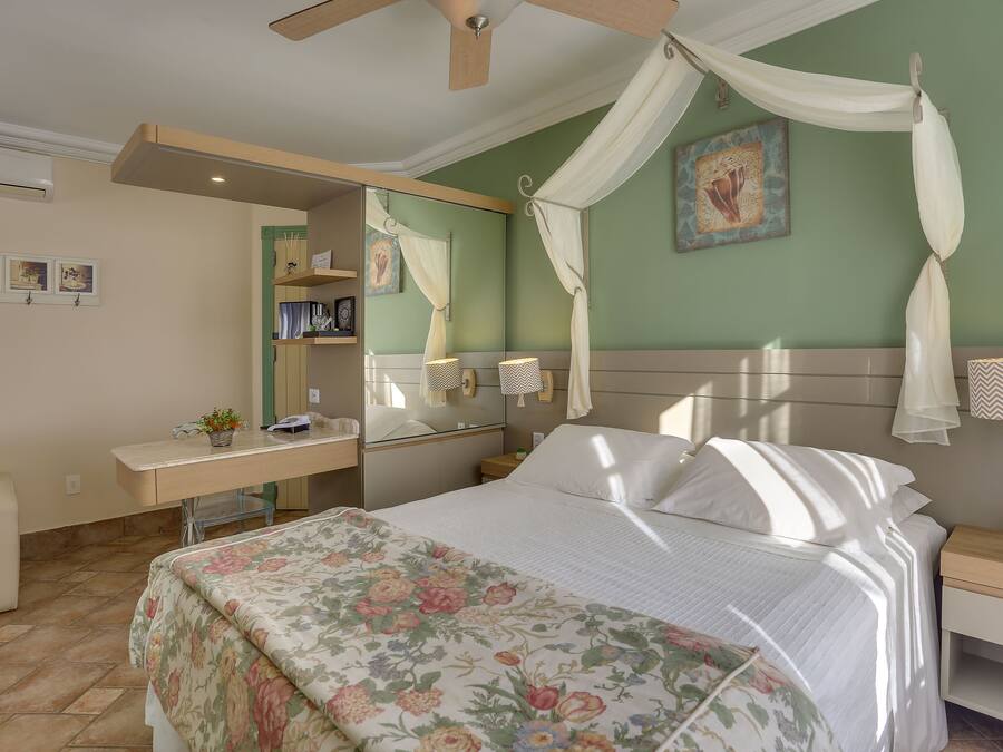 A bedroom with a bed, a desk, a chair, a nightstand, and a ceiling fan.