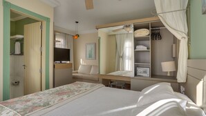 Un dormitorio ordenado con cama, tocador, espejo y armario.