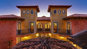 Un edificio simétrico con un patio central, techo de tejas y varios balcones con barandillas.