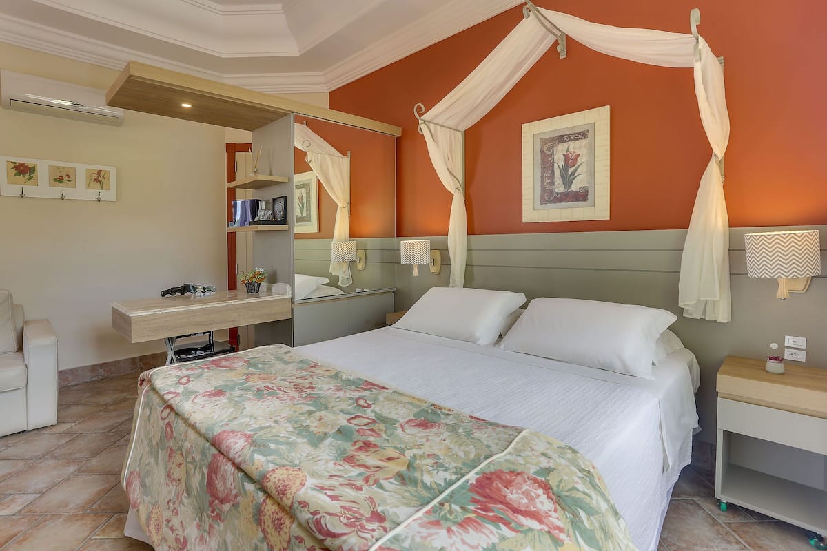 Un dormitorio con cama, escritorio, silla, tocador y espejo.