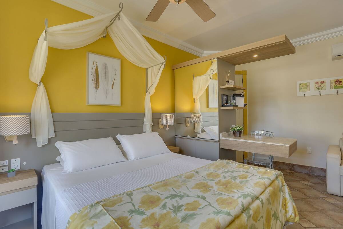 Un dormitorio con cama con dosel, mesitas de noche, escritorio y espejo.