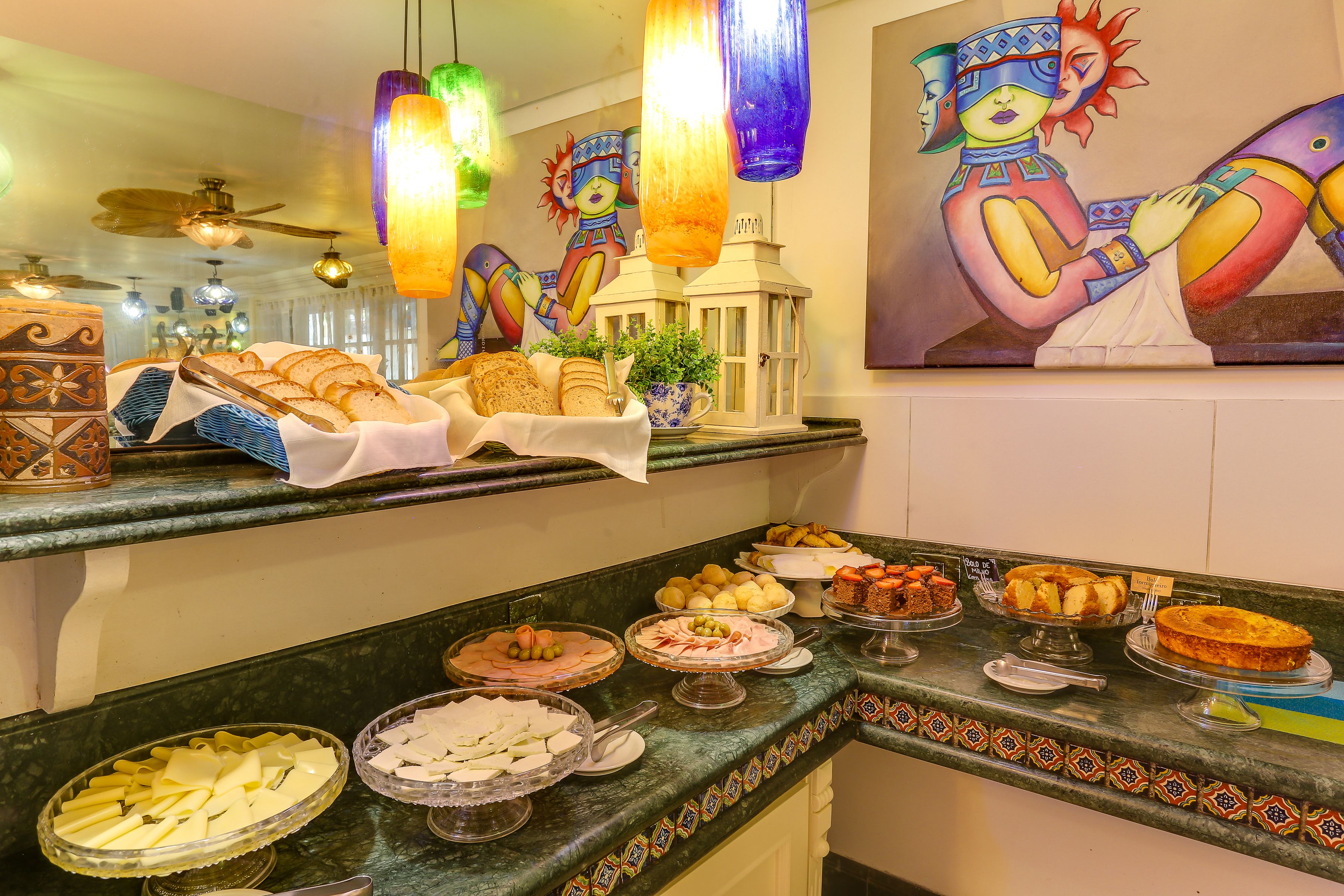 A buffet with various food items and a decorative painting on the wall.