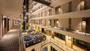 Vestíbulo de hotel de varios niveles con un atrio central, zonas de estar y una escalera.