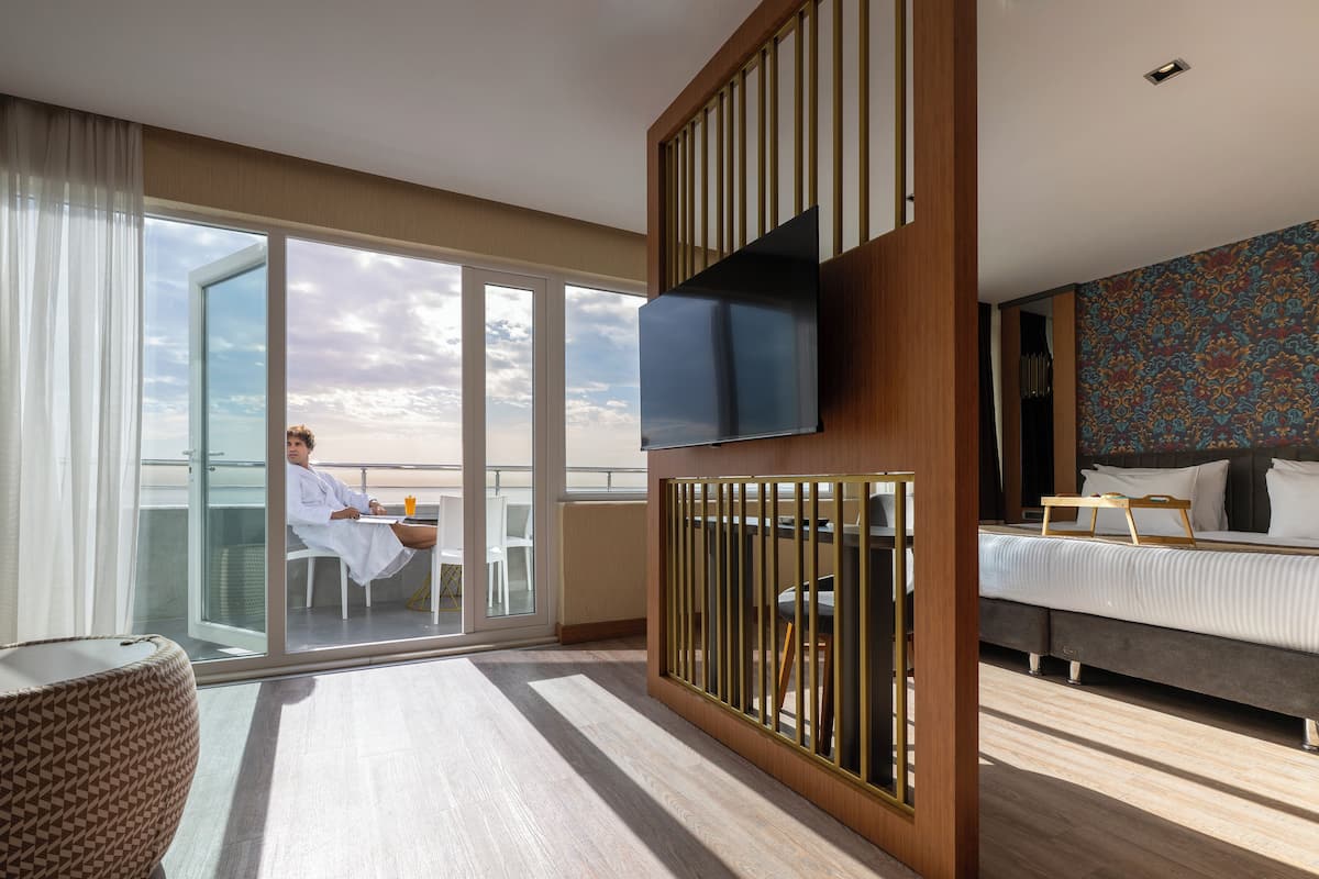 Ein modernes Hotelzimmer mit Balkon, einem Bett, einem Fernseher und einer Wand mit Muster.