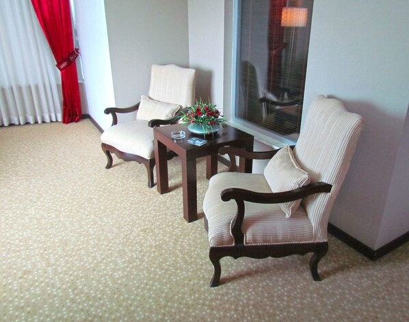 A room with two armchairs, a small table with a vase of flowers, and a large window. - Sealife Family Resort Hotel (Konyaalti)