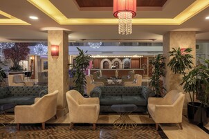 A lobby with plush seating, a chandelier, and a reception area in the background.