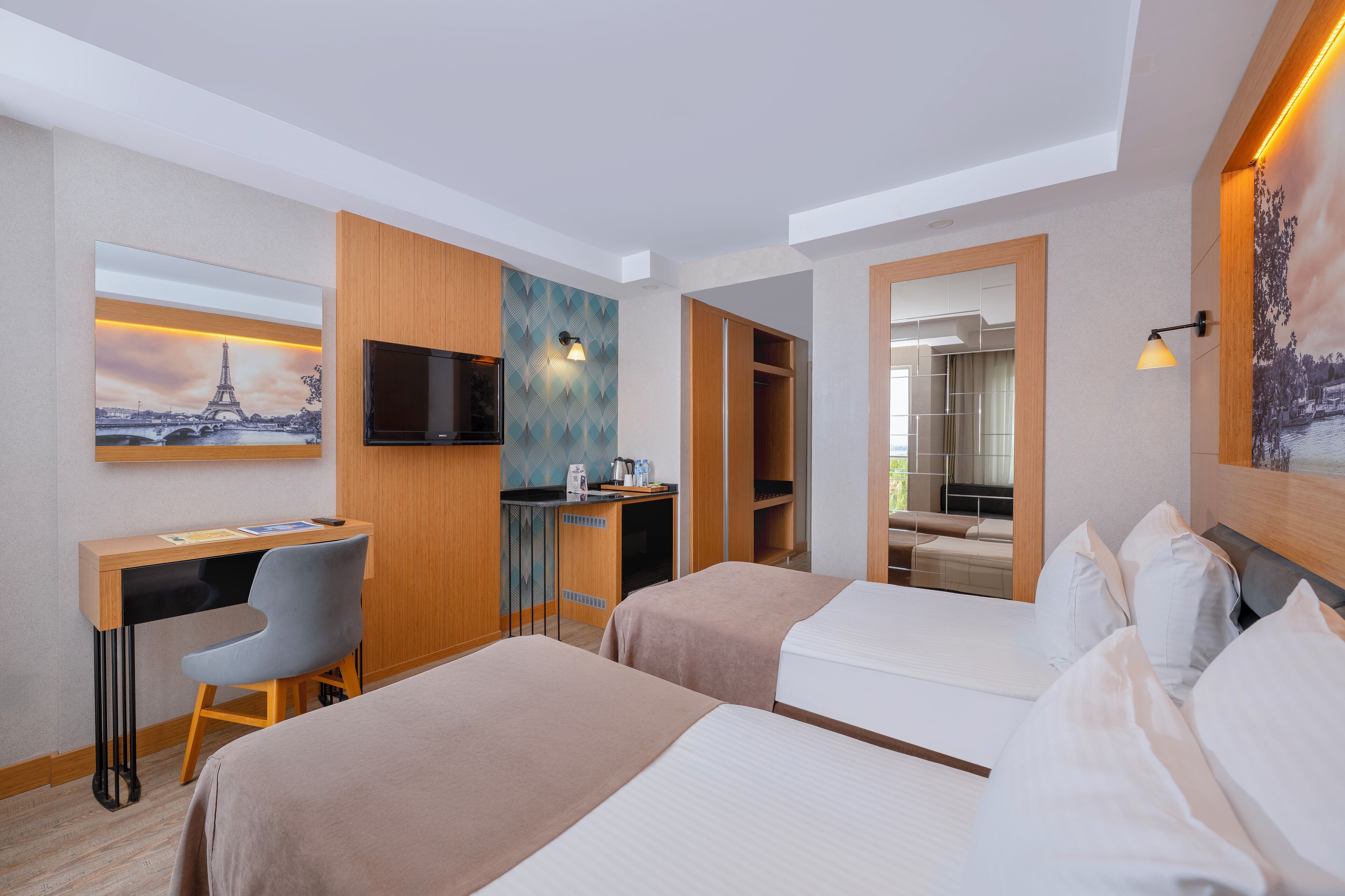 Habitación de hotel con dos camas, un escritorio con silla, televisión y armario.