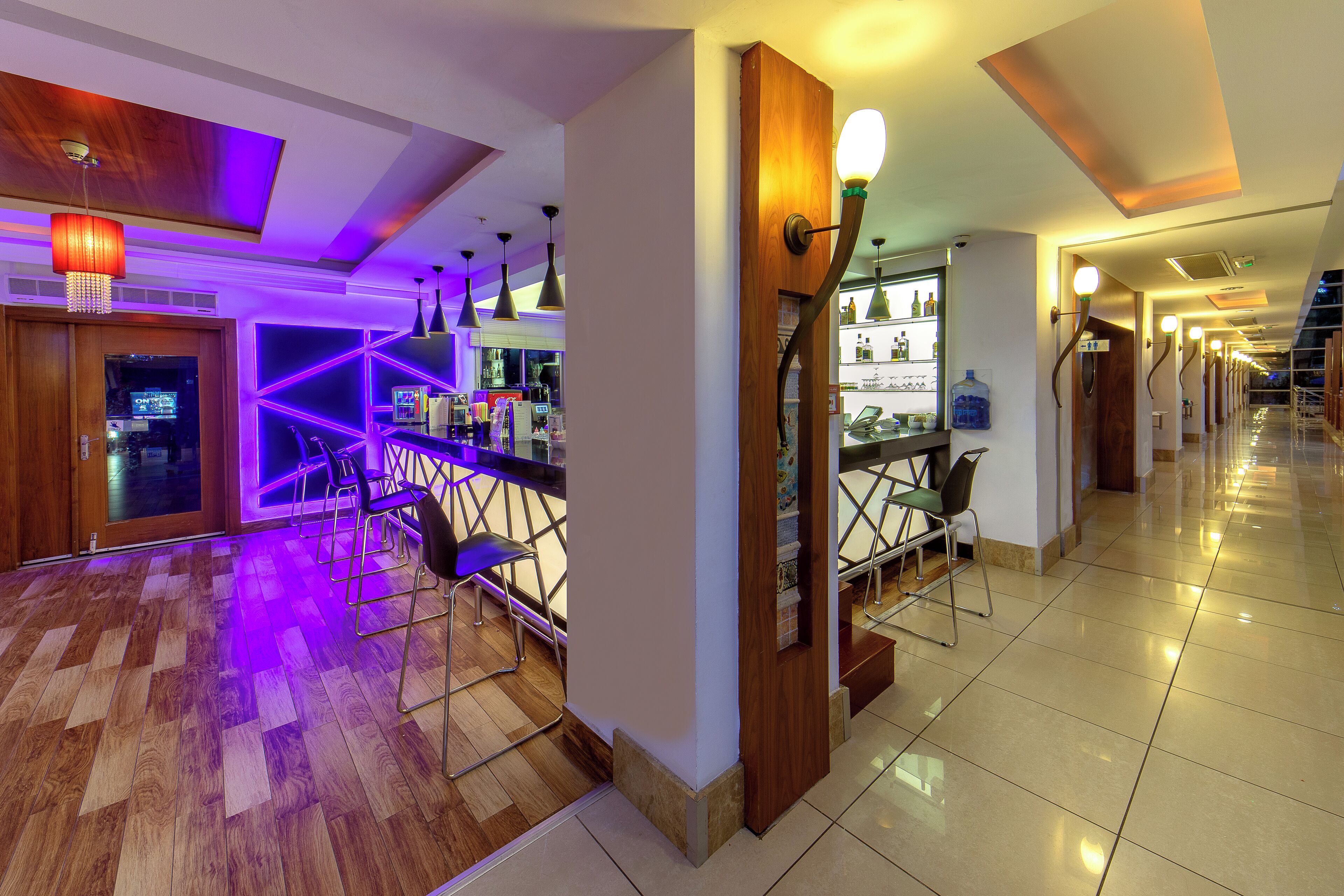 Een moderne hotellobby met een bar, houten vloeren en tijdloze verlichting.