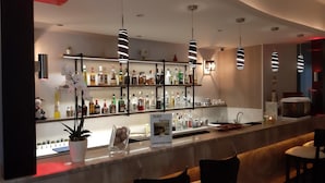 A bar area with shelves of liquor bottles, a menu board, and seating with chairs. - Paritsa Hotel (Kos)