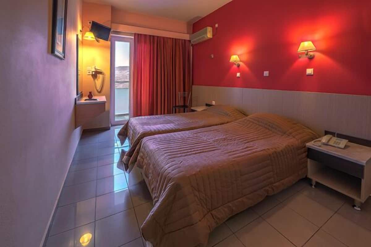 A hotel room with two beds, a TV, a desk, and a phone.